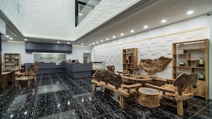 A modern hotel lobby with a reception desk, wooden furniture, and a decorative wall with geometric patterns. - Jeju 29 Pool Villa (Jeju City)
