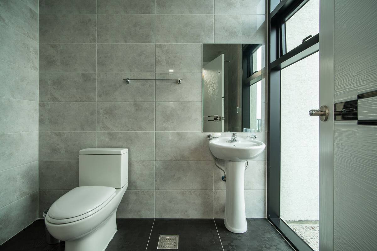 A modern bathroom with a toilet, sink, and large window.