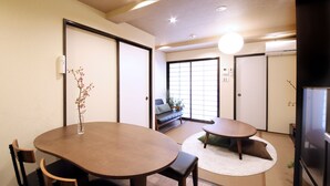 A traditional Japanese-style room with tatami flooring, a low table, and a sofa. - Guest House Nishijin Yui (Kyoto)