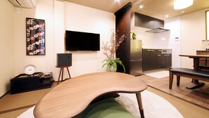 A modern kitchen with a flat-screen TV, a dining table, and a bench. - Guest House Nishijin Yui (Kyoto)