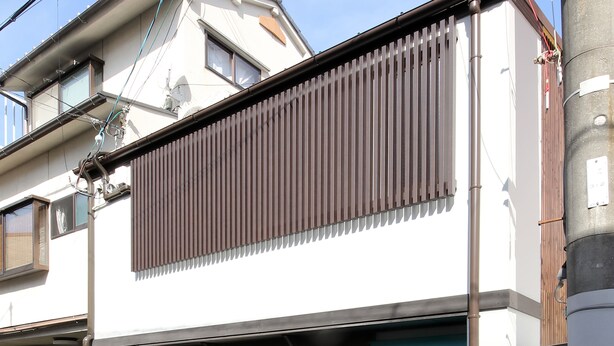 Un edificio de dos pisos con fachada marrón, un toldo azul y un letrero que dice 'Guest House'.