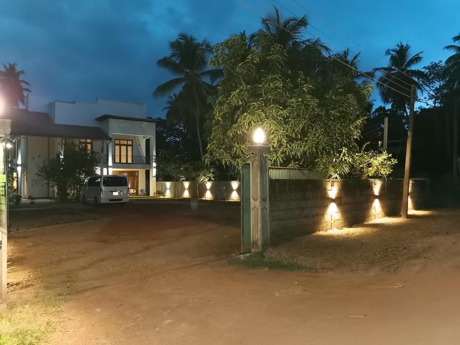 A gated residential area with a white building, a parked van, and a well-lit entrance.
