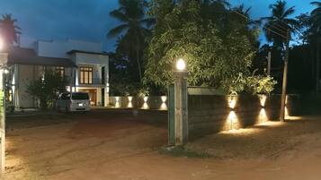 A gated residential area with a white building, a parked van, and a well-lit entrance.