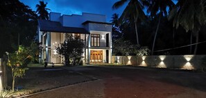Une maison moderne à deux étages, dotée d’une entrée bien éclairée et d’une allée pavée.