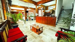 Um hall com painéis de madeira, balcão de recepção e áreas de estar.