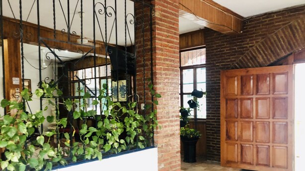 Um quarto com parede de tijolos, porta de madeira e chão de azulejos.
