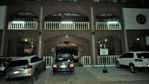Um edifício com fachada de tijolos, janelas em arco e varanda com grades.