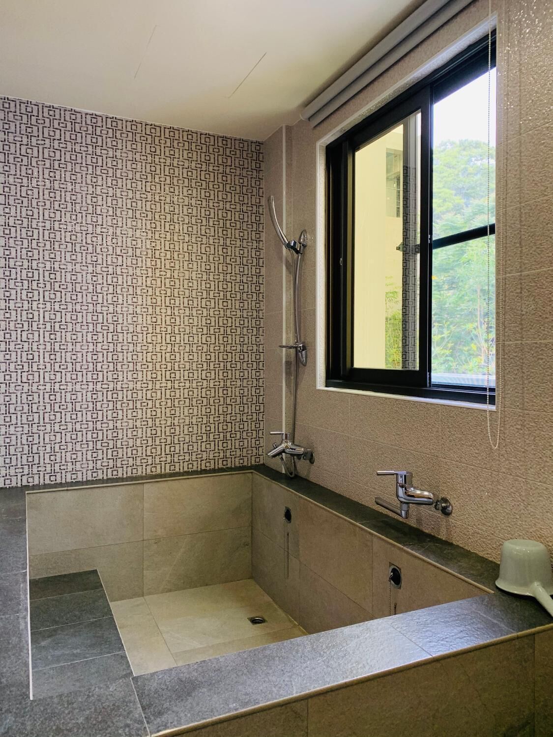 A modern bathroom with a shower, a sink, and a window.