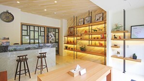 A modern kitchen with wooden bar stools, a marble countertop, and a wooden dining table. - Yuan Ju Boutique Hotel (Yuchi)