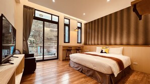 A modern hotel room with a large bed, a desk with a computer, and a balcony with a view of trees. - Yuan Ju Boutique Hotel (Yuchi)