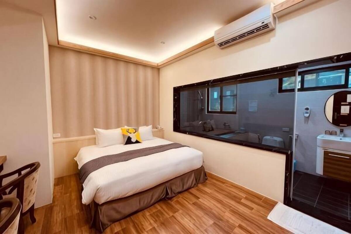 A hotel room with a bed, a desk, a mirror, and a window.