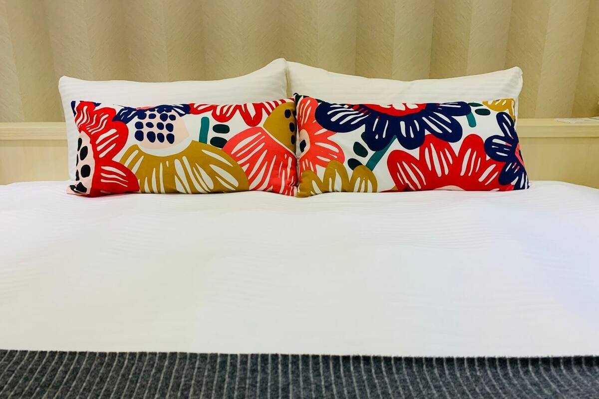 A bed with two colorful pillows and a striped rug.