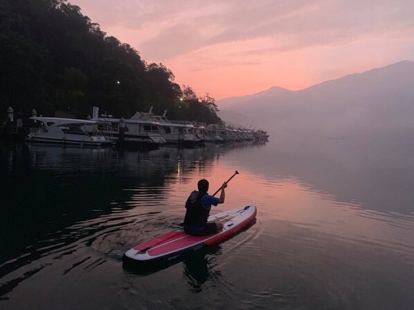 A person paddling a paddleboard near a dock with boats. - Yuan Ju Boutique Hotel (Yuchi)