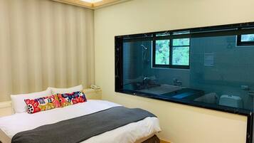 A bedroom with a bed, a bedside table, a window, and an air conditioning unit.