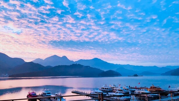 A marina with boats docked, a calm lake, and mountains in the background. - Yuan Ju Boutique Hotel (Yuchi)
