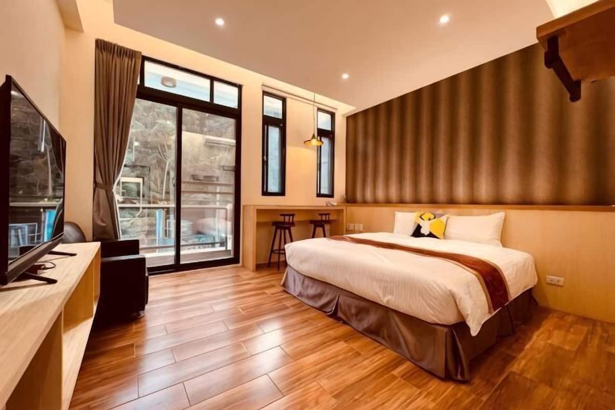 A hotel room with a bed, a desk, a TV, and a window with curtains.