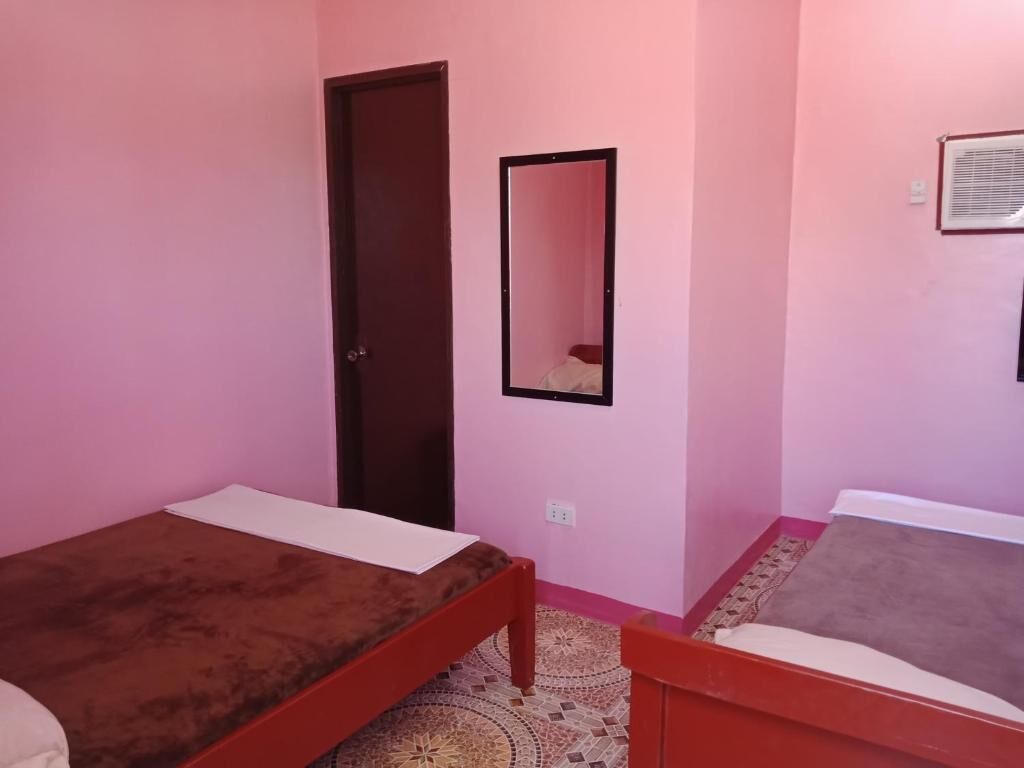 Una habitación con dos camas individuales, una puerta, un espejo y un suelo con estampado.