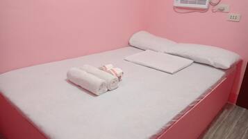 A single bed with white linens, a white pillow, and a rolled towel.