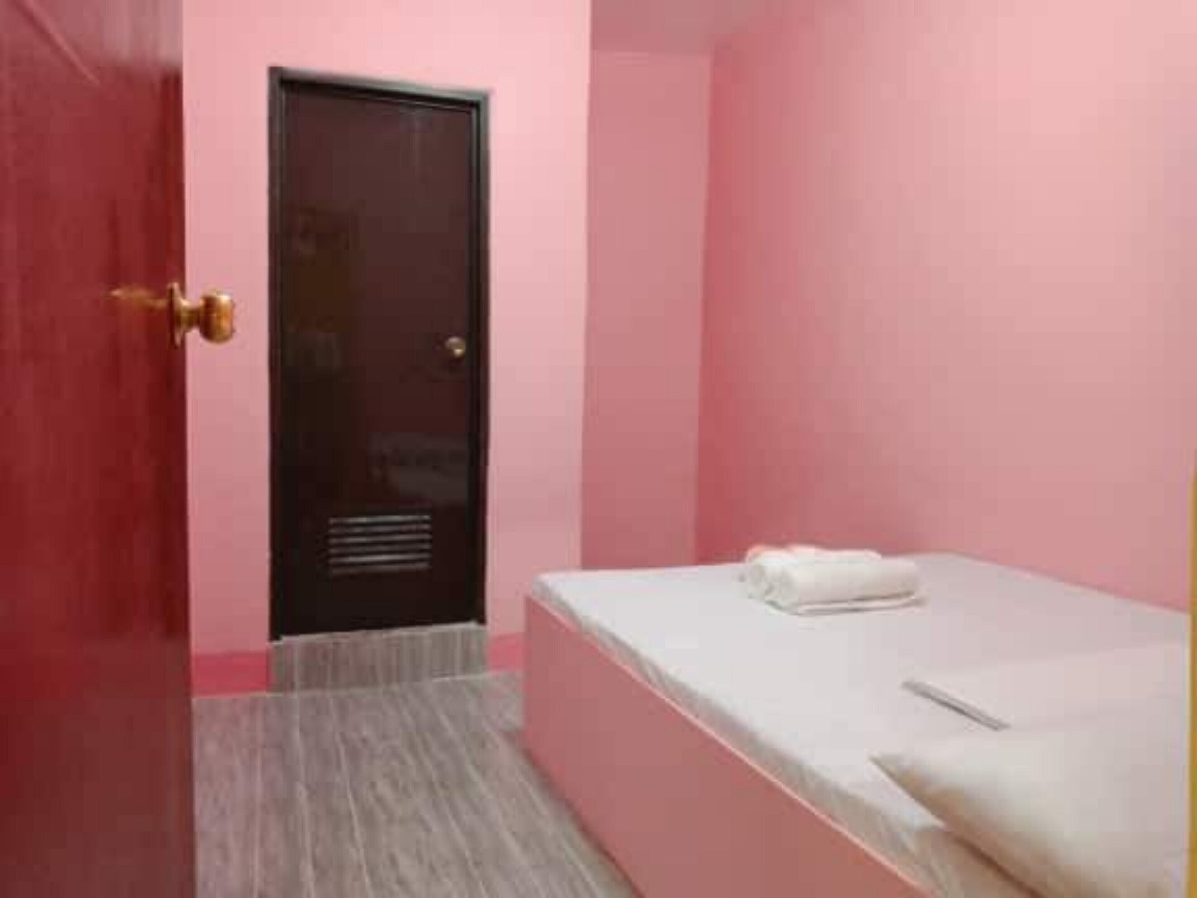 Una habitación con una cama, una puerta y un ventanal pequeño.