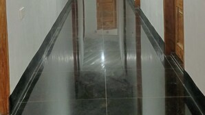 A hallway with glossy black tiled floors, wooden doors, and white walls. - Ludy's Pension House (Carles)