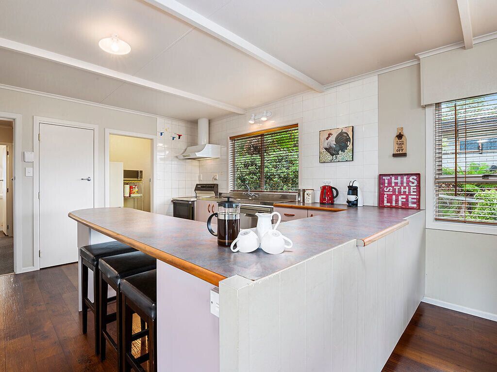A modern kitchen with a central island, bar stools, a coffee maker, and a sign that reads "THIS LIFE".