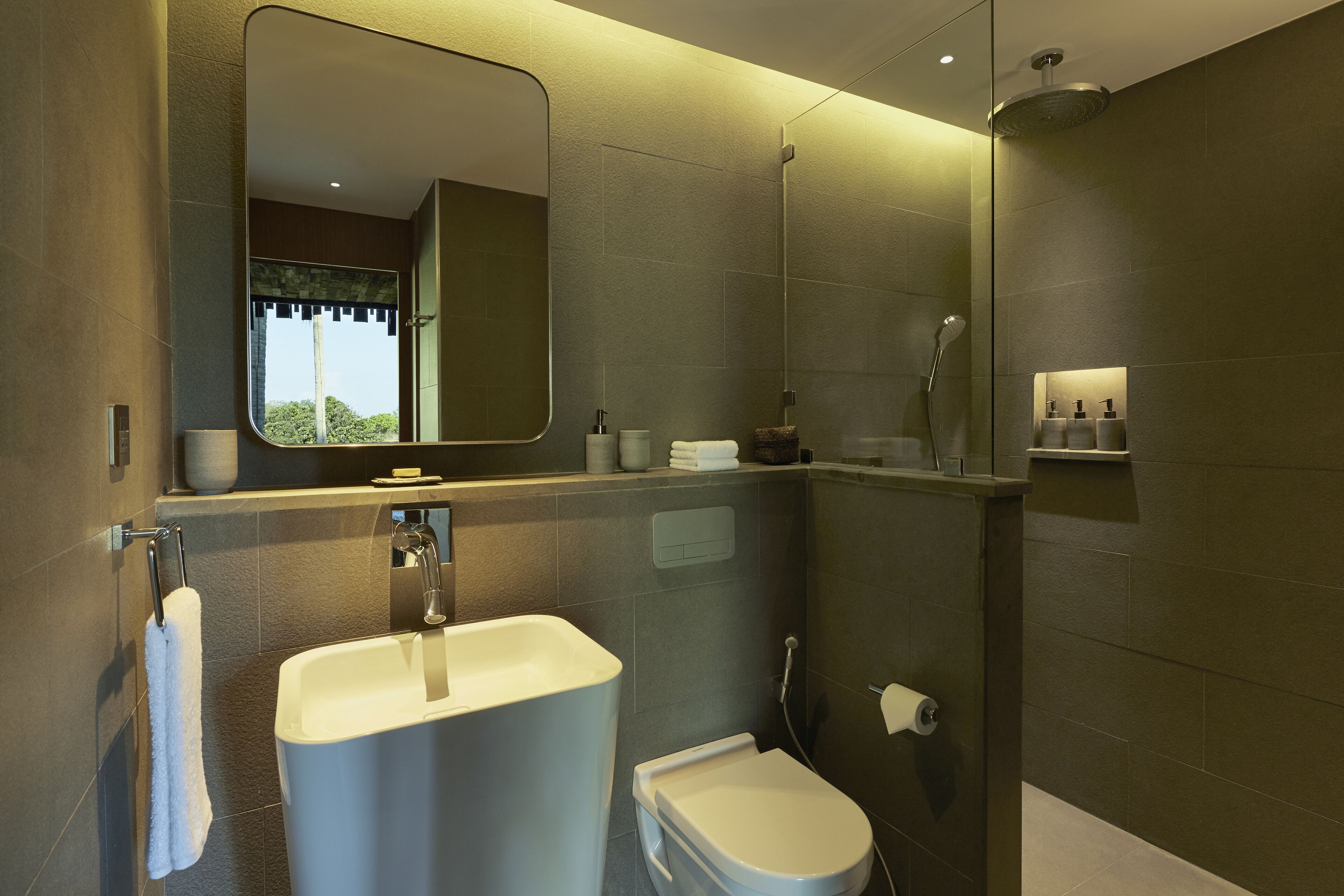 A modern bathroom with a large mirror, a bathtub, a toilet, and a shower area.