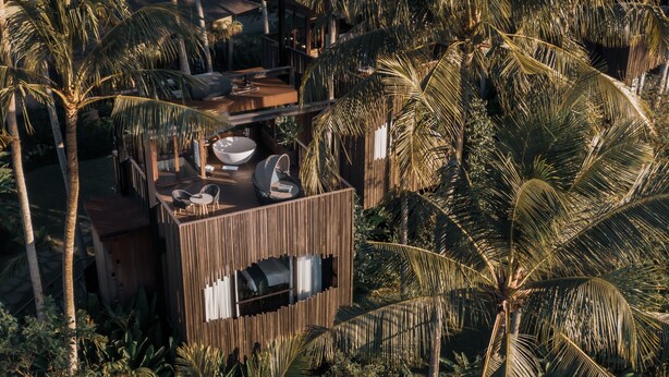 Een modern buitenverblijf met een houten terras, zitplaatsen en een grote schaal.