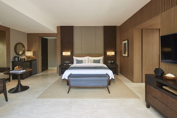 A modern hotel room with a large bed, bedside tables, a TV, and a seating area. - Nirjhara (Tabanan)