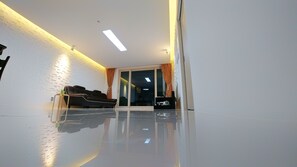 Una sala de estar moderna con un sofá de cuero negro, una mesa de centro de vidrio y un amplio ventanal corredera que da a un balcón.