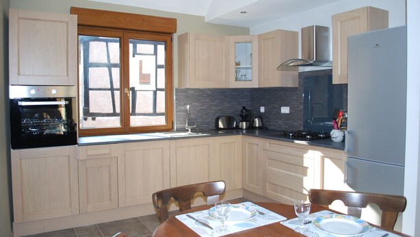 Una cocina moderna con armarios de madera, horno empotrado, estufa y refrigerador.