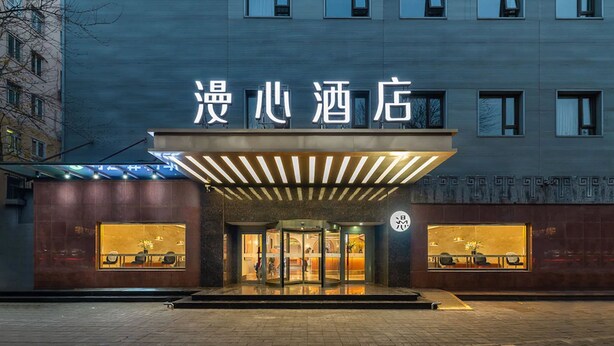 A hotel entrance with a modern facade, large windows, and a prominent sign. - Manxin Hotel Beijing Forbidden City (Beijing)