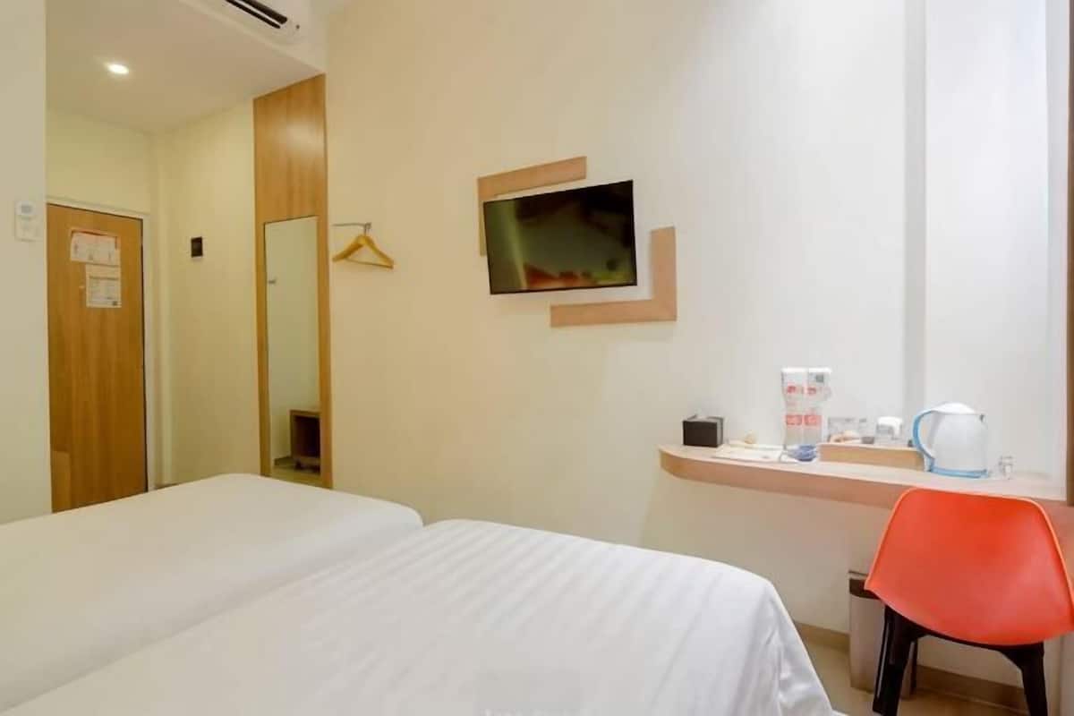 A hotel room with two beds, a TV, a desk with a coffee maker, and a mirror.