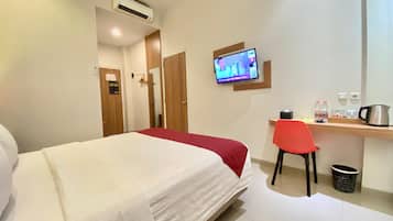 Een hotelkamer met een bed, een bureau met stoel, een televisie en een koffiezetapparaat.