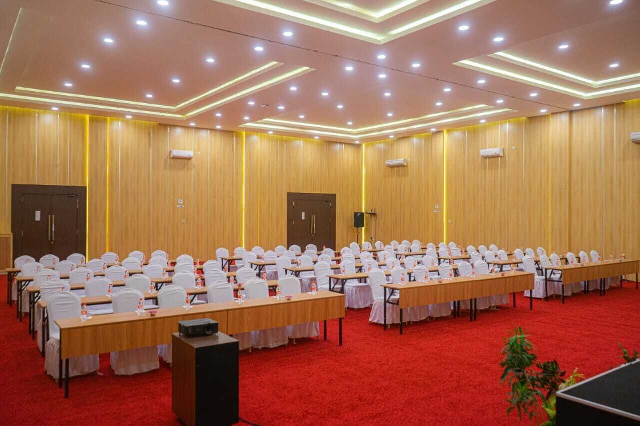 A conference room with rows of tables and chairs, equipped with microphones and speakers.