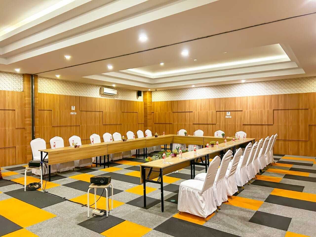 A conference room with a long table, white chairs, and a patterned carpet.