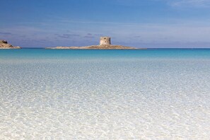 A clear turquoise sea with a small island featuring a stone tower.