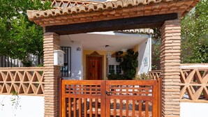 Una casa tradicional con fachada de ladrillo, un portón de madera y un acceso con tejas.