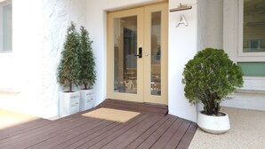 A building entrance with a glass door, a wooden deck, and potted plants. - OYO Myeongdong 5 Lodge (Seoul)