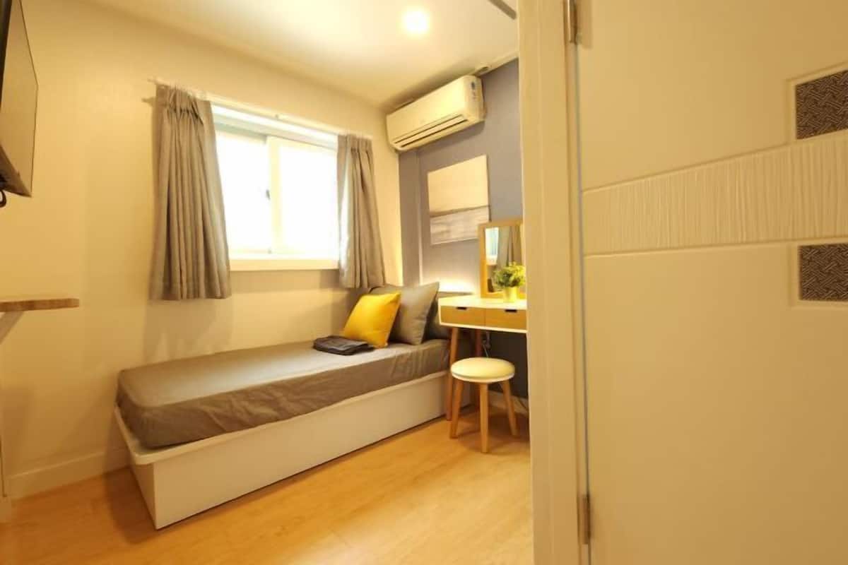 A compact bedroom with a bed, a desk, and a chair.
