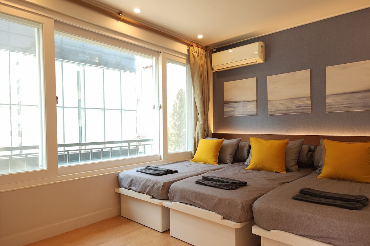 A bedroom with two beds, a large window, and an air conditioning unit.