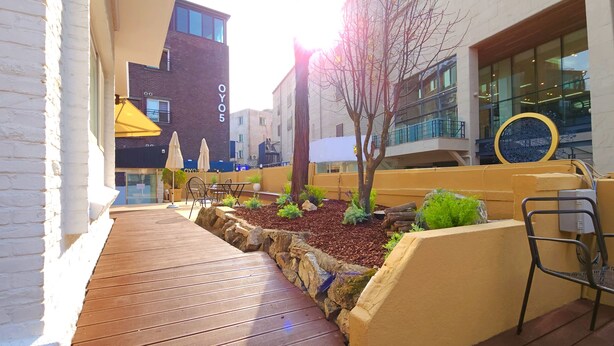 A wooden deck with outdoor seating, a tree, and a building with 'OY05' signage. - OYO Myeongdong 5 Lodge (Seoul)