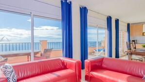 A balcony with red leather sofas, a dining table, and blue curtains.
