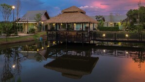 A thatched-roof structure with outdoor seating, a pool, and a sunset sky. - Loftpical Resort (Ko Kaeo)