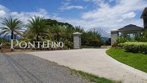 Une entrée fermée par un portail, sur laquelle on peut lire l’inscription « PONTEHINO », et un chemin menant à un bâtiment au design moderne.