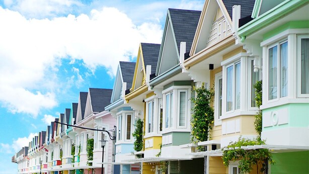 Une rangée de maisons colorées, chacune ayant un style architectural distinct, sous un ciel dégagé.