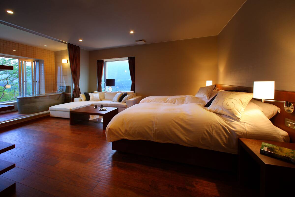 Ein geräumiges Hotelzimmer mit einem großen Bett, einer Couch und einem Esstisch.