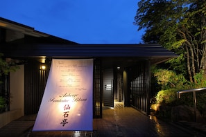 A building entrance with a banner displaying a menu in multiple languages. - Fontaine Bleau Sengokutei (Hakone)