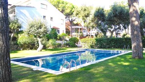 A rectangular swimming pool with a metal ladder, surrounded by grass and trees. - 1PX 65 - Cozy house for 8 people with communal pool only 800m from the Calella de Palafrugell beach (Calella de Palafrugell)