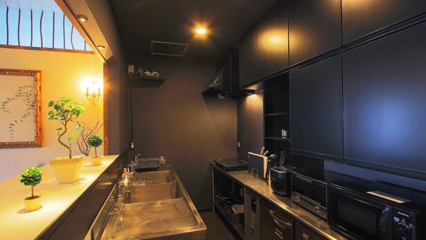 A modern kitchen with stainless steel appliances, a long counter, and potted plants. - Fujinokura Tiny Fort (Fujiyoshida)
