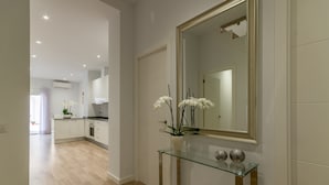 Un intérieur moderne avec une console en verre, un grand miroir et des orchidées blanches.